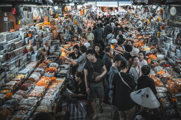 Busy indoor market filled with shoppers and colorful goods.