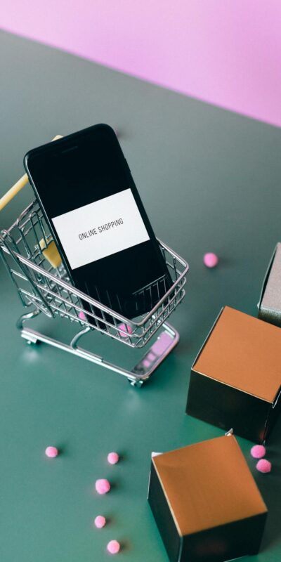 Conceptual image of online shopping with a smartphone in a miniature cart.